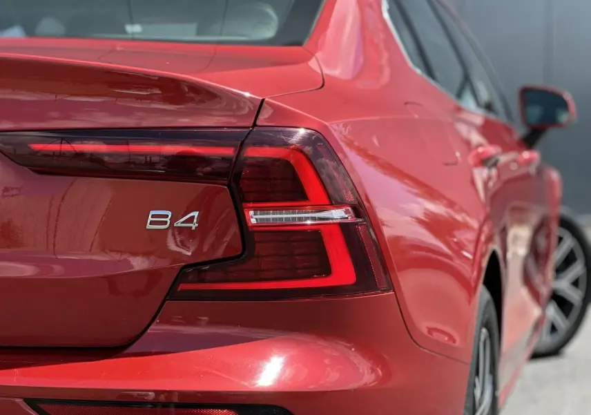 Gros plan sur l'arrière droit rouge Fusion du Volvo S60 B4 2024, avec feu arrière LED et logo B4 visible.