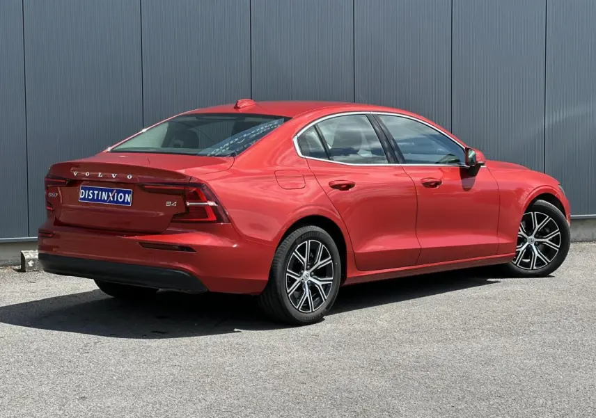Vue 3/4 arrière droite d'une Volvo S60 rouge Fusion avec jantes alliage 17 pouces et contours de fenêtres chromés.