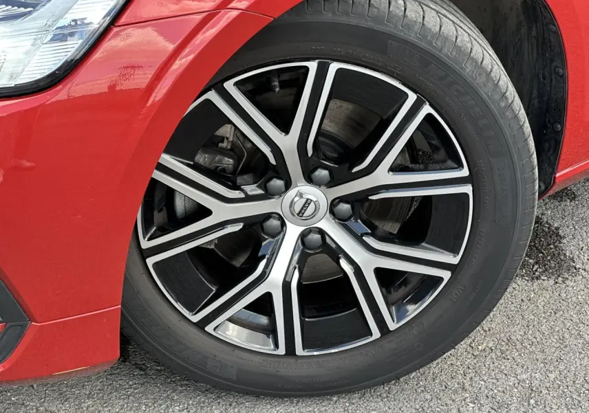 Gros plan sur la jante alliage 17 pouces noir et diamant du côté avant gauche d’une Volvo S60 Rouge Fusion 2024.