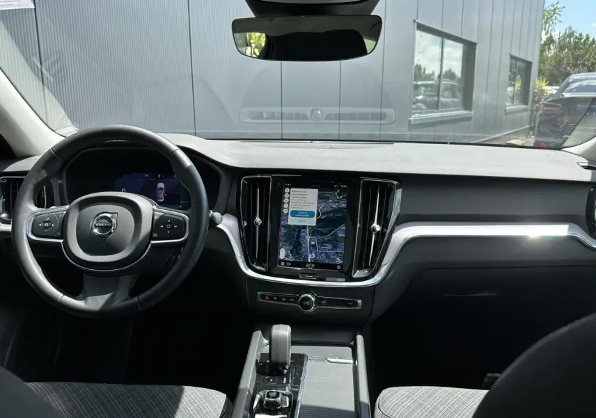 Vue intérieure avant du tableau de bord de la Volvo S60 rouge Fusion 2024 avec écran tactile GPS et volant multifonction.