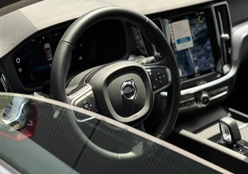 Vue rapprochée du volant et du tableau de bord numérique d'une Volvo S60 2024 avec écran tactile vertical.