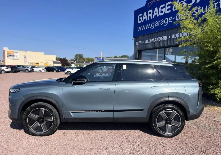 Vue de profil côté gauche du SUV JAECOO J7 gris olive, avec vitres arrière surteintées et jantes modernes noires.