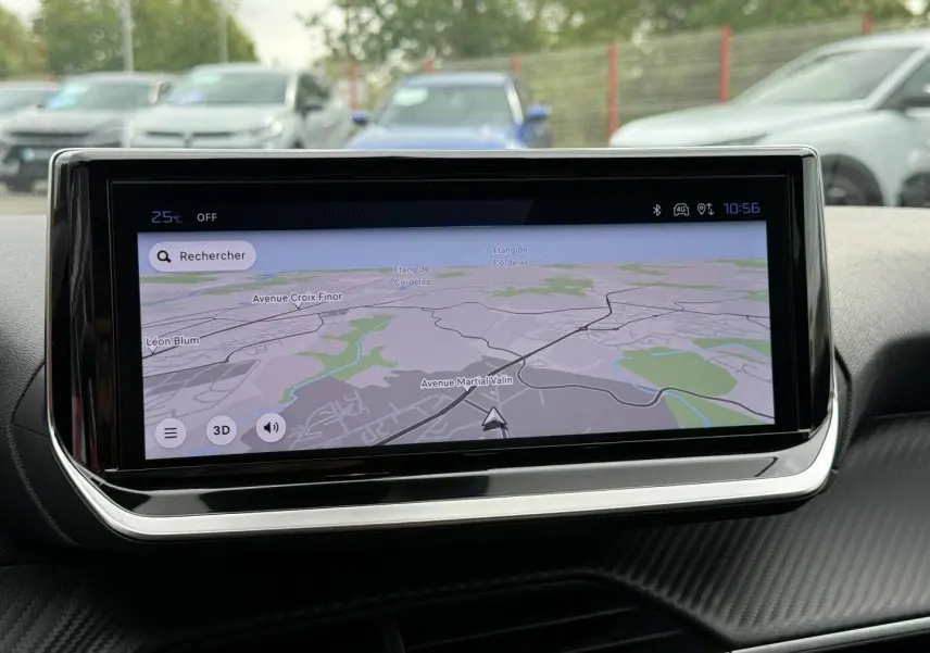 Vue intérieure centrée sur l'écran tactile du système de navigation de la Peugeot 208 2025, avec reflet extérieur flou.