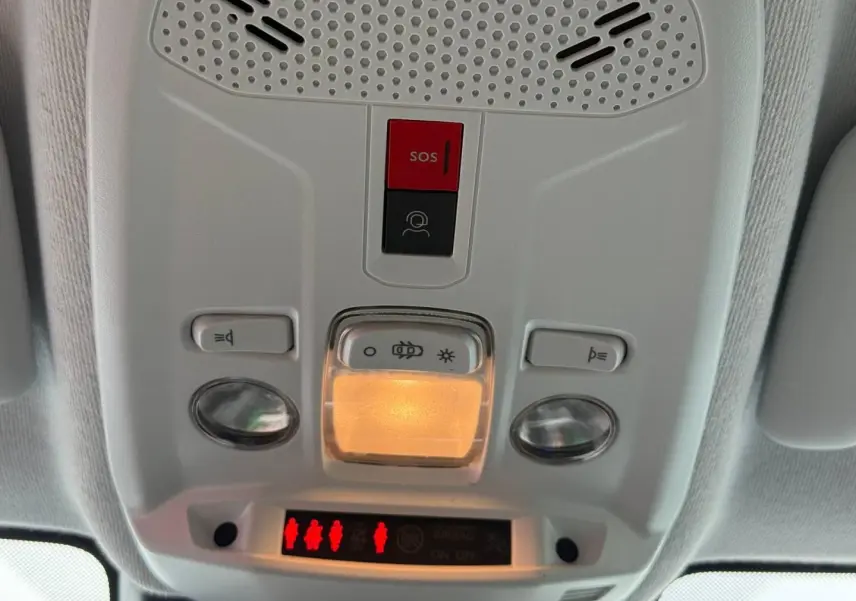 Vue en gros plan du plafonnier intérieur gris avec bouton SOS rouge et éclairage allumé dans une Peugeot 208 2025.