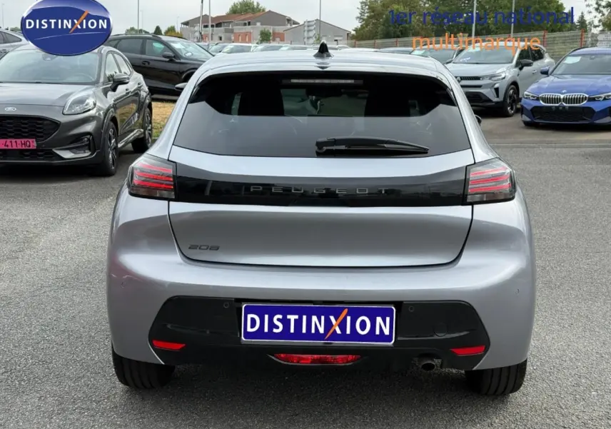 Vue arrière d'une Peugeot 208 gris Artense avec feux arrière LED et lunette arrière surteintée, en extérieur sur parking.