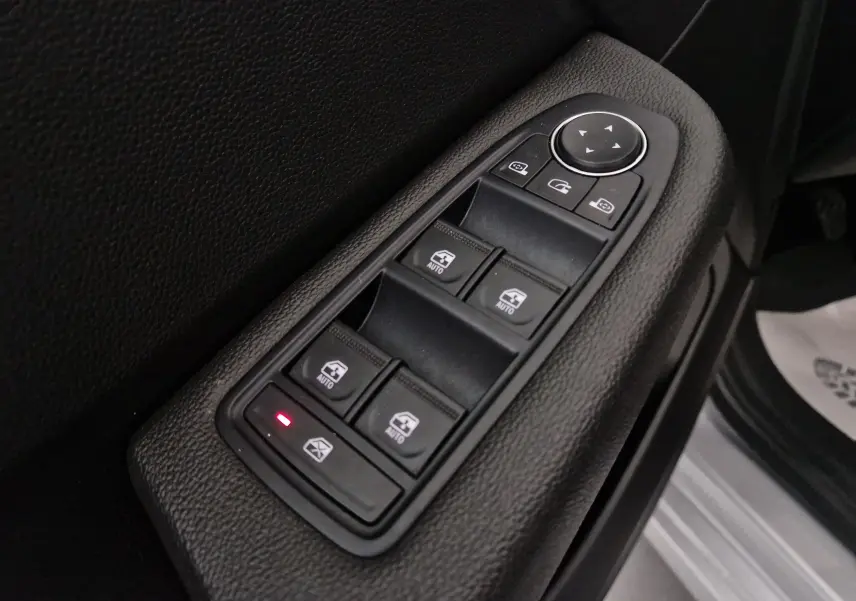 Gros plan sur les commandes de lève-vitres et rétroviseurs électriques côté conducteur d'une Renault Clio V gris platine.