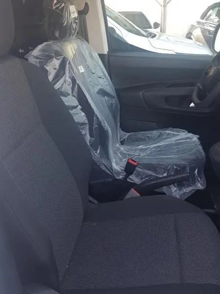 Vue intérieure côté droit du siège conducteur du Citroën Berlingo blanc 2025, siège protégé par film plastique.