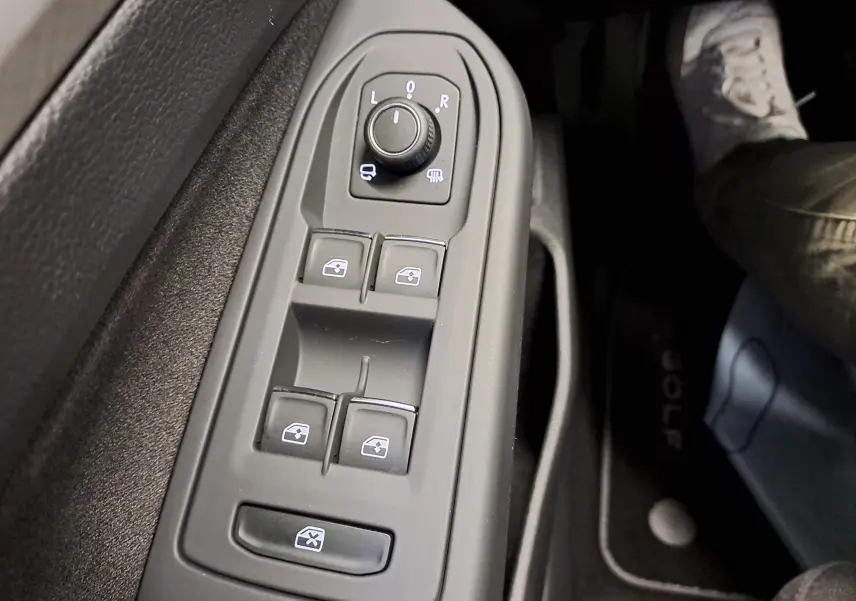 Gros plan sur les commandes des vitres et rétroviseurs côté gauche dans une Volkswagen Golf 1.5 eTSI 2025.
