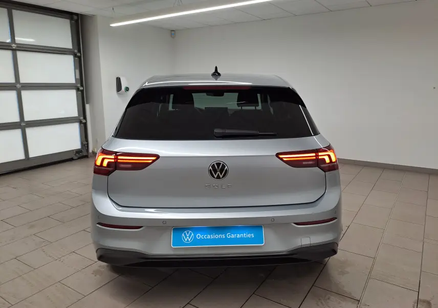 Vue arrière d'une Volkswagen Golf 1.5 eTSI 2025 en Argent Dolomite avec feux LED allumés dans un garage.