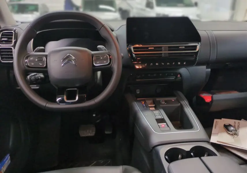Vue intérieure avant du tableau de bord noir et volant Citroën du C5 Aircross Hybrid avec écran tactile central.