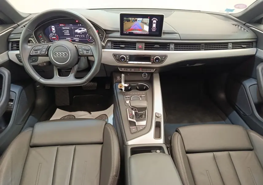Intérieur Audi A5 40 TFSI 2019 vu de face, tableau de bord moderne avec écran central et sièges cuir noirs.