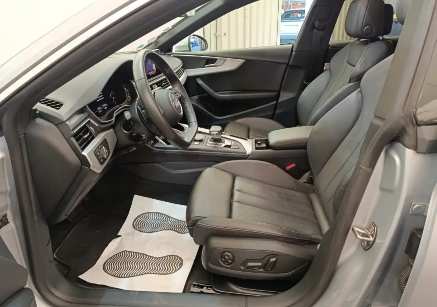 Intérieur avant droit d'Audi A5 gris clair 2019, sièges cuir noirs et tableau de bord moderne avec volant multifonction.