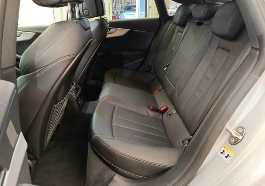 Vue côté droit de la banquette arrière en cuir noir de l'Audi A5 gris clair, avec ceintures et appuie-têtes visibles.