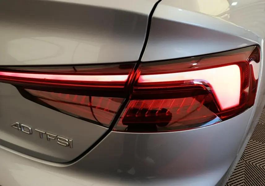 Gros plan sur le feu arrière droit rouge et le logo 40 TFSI d’une Audi A5 gris clair de 2019.