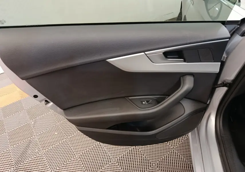 Vue intérieure de la porte avant gauche d'une Audi A5 gris clair, avec garniture noire et insert argenté.