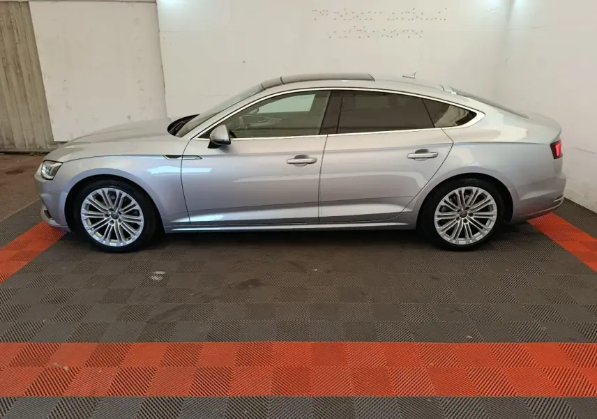 Audi A5 gris clair vue de profil côté gauche, avec jantes alliage et vitres teintées dans un garage.