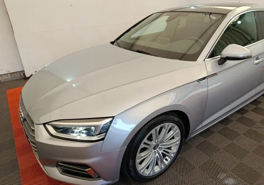 Audi A5 gris clair vue 3/4 avant droit, mettant en valeur les phares LED et la calandre distinctive.