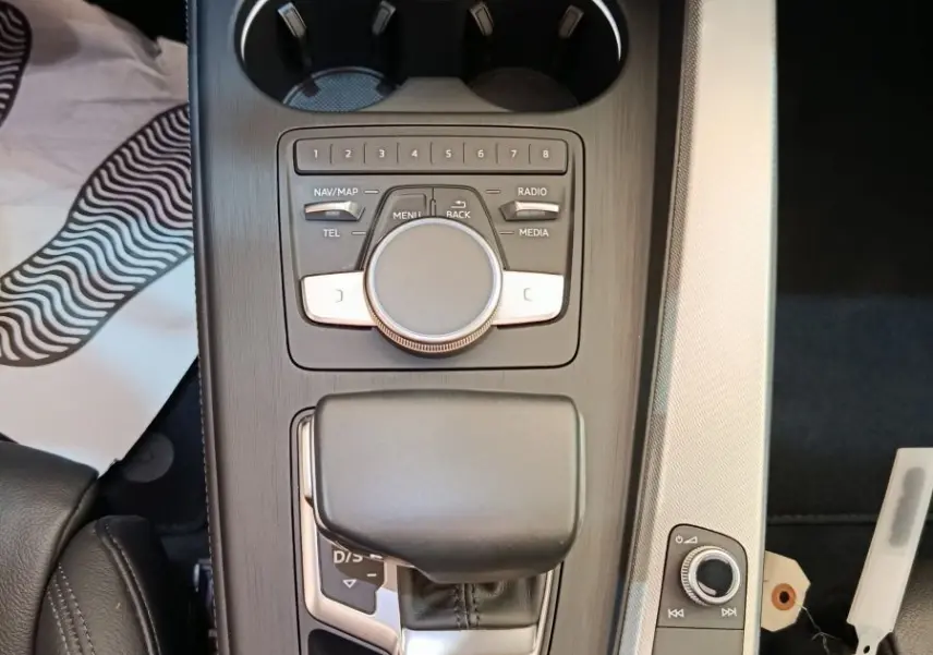 Vue plongeante sur la console centrale noire et argentée de l'Audi A5 2019 avec commandes multimédia et levier de vitesse.