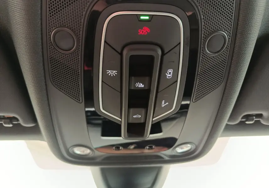 Vue en contre-plongée du panneau de commandes de toit intérieur noir avec boutons d’éclairage et SOS sur Audi A5 gris clair.