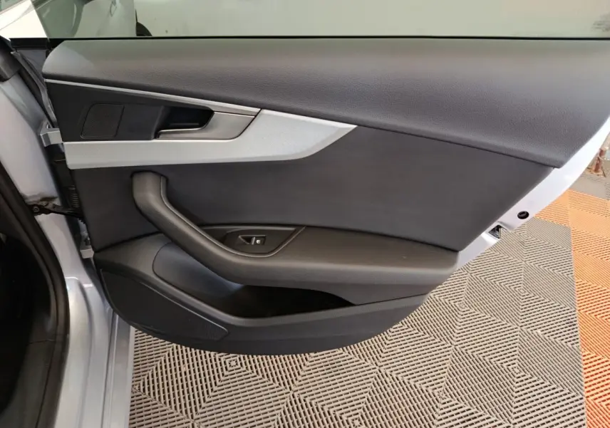 Vue intérieure de la porte avant gauche gris clair de l'Audi A5 40 TFSI avec garniture noire et insert argenté.