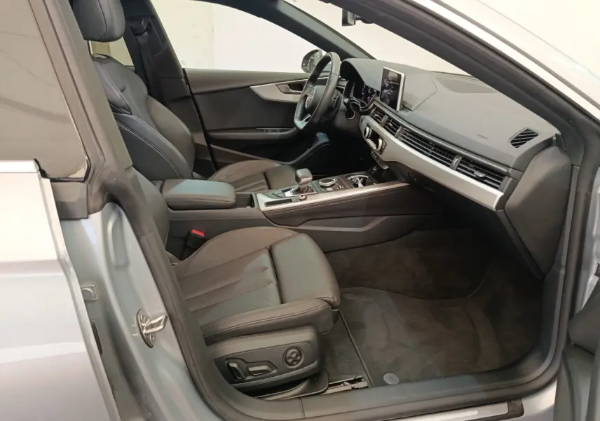 Intérieur côté conducteur d’Audi A5 gris clair, sièges cuir noirs et tableau de bord moderne avec écran central.