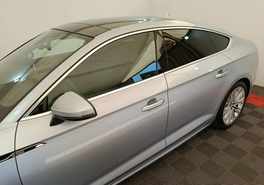 Vue latérale droite d'une Audi A5 gris clair avec vitres teintées et jantes alliage multibranches.