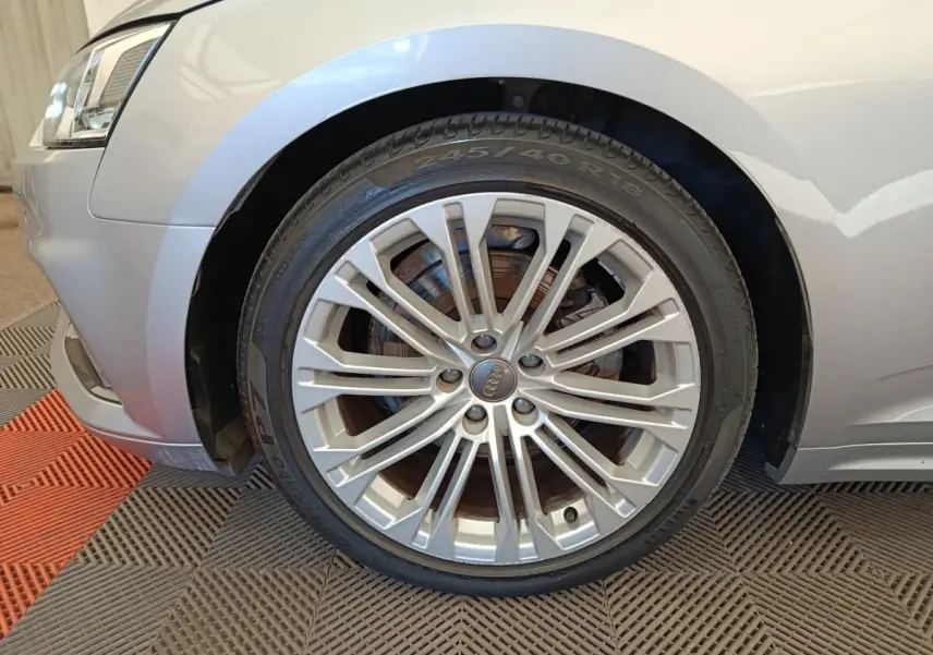 Gros plan sur la roue avant gauche et l'aile gris clair d'une Audi A5 40 TFSI 2019 avec jante alliage multibranches.