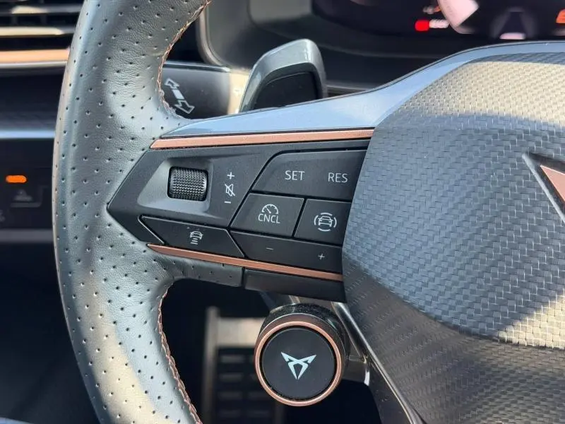 Détail du volant perforé noir du CUPRA Formentor 2025 avec commandes de régulateur et logo cuivré central.