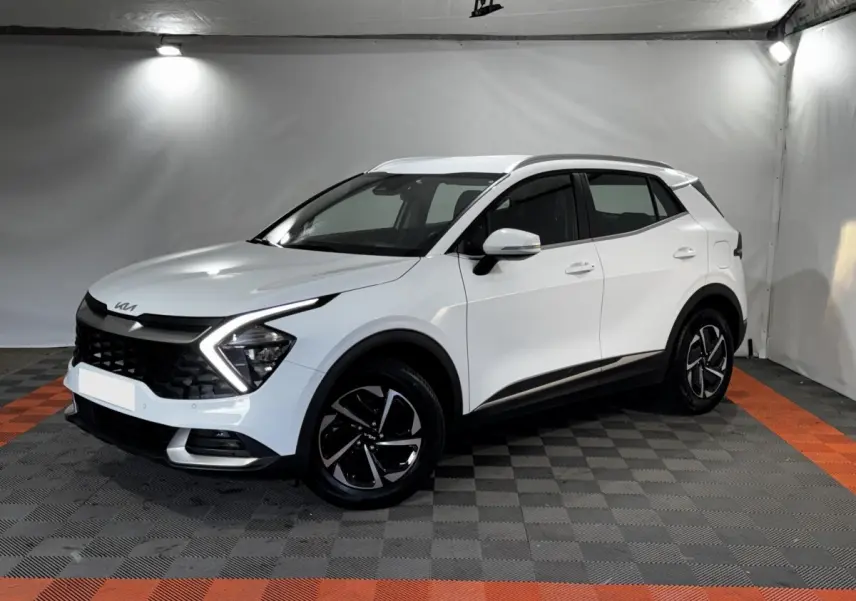 KIA Sportage blanc en 3/4 avant droit, avec signature lumineuse en forme de flèche et jantes noires distinctives.