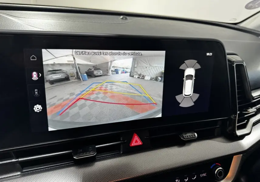 Écran tactile intérieur montrant la caméra de recul et l'aide au stationnement du Kia Sportage blanc 2024.