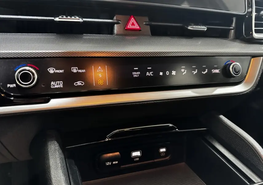 Détail du tableau de bord noir du Kia Sportage 2024 avec commandes climatisation digitales et ports USB et 12V.