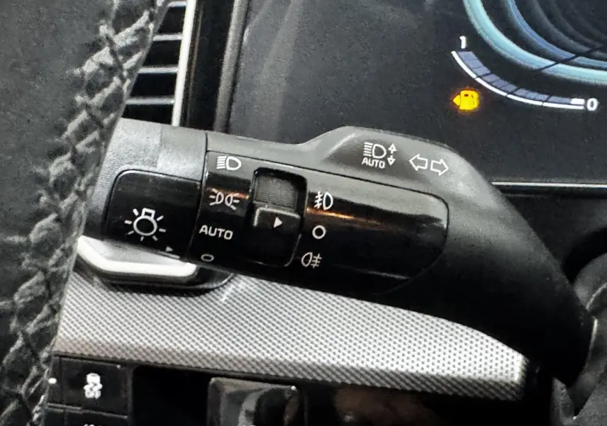 Gros plan sur la commande des phares et clignotants à gauche du volant dans un Kia Sportage 2024.