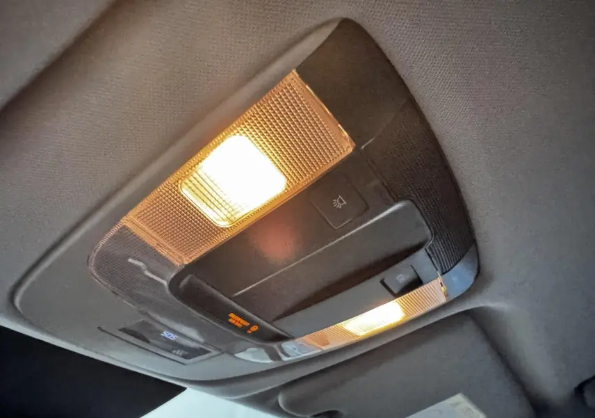 Plafonnier intérieur allumé du Kia Sportage blanc 2024, vue en léger contre-plongée sur la console de toit.