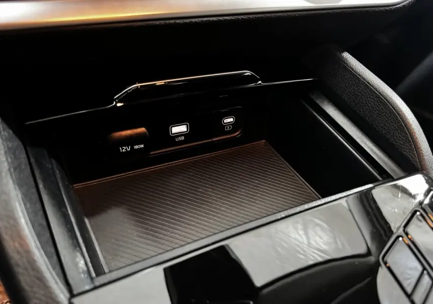 Détail de la console centrale noire du Kia Sportage 2024 avec prises USB et 12V visibles en gros plan.