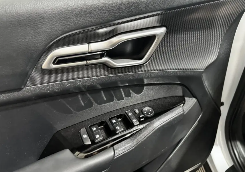Gros plan sur la porte avant gauche blanche du Kia Sportage 2024, montrant la poignée argentée et les commandes de vitres noires.