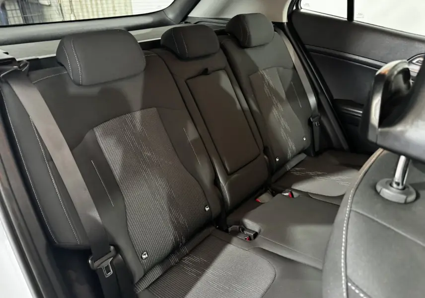 Vue intérieure côté arrière droit montrant la banquette noire avec appuie-têtes et ceinture de sécurité du Kia Sportage 2024 blanc.