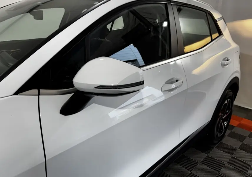 Vue côté gauche du Kia Sportage blanc 2024, mettant en valeur la porte arrière et le rétroviseur avec clignotant intégré.