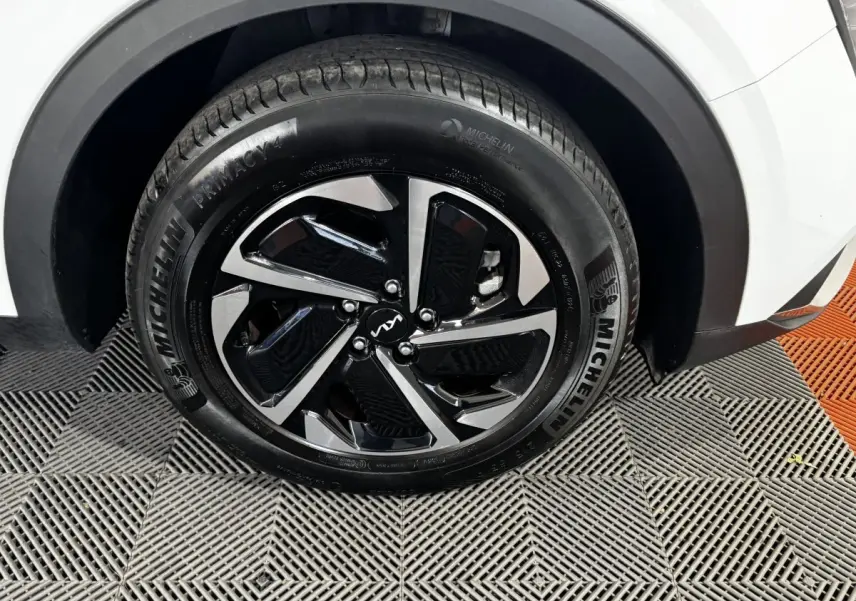 Gros plan sur la roue avant droite du KIA Sportage blanc, avec jante noire et argent et pneu Michelin.