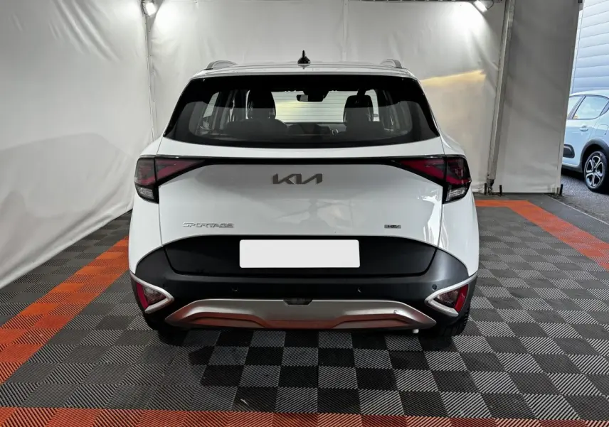 Vue arrière d'un KIA Sportage blanc 2024 avec feux arrière en forme de flèche et logo KIA central.