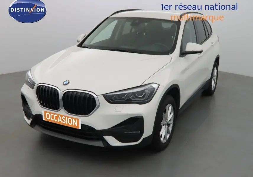 BMW X1 blanc Alpine metal vue 3/4 avant droit avec calandre noire et jantes argentées en intérieur studio