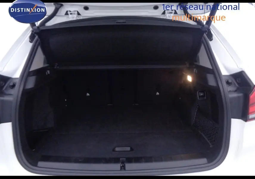 Coffre ouvert d'un BMW X1 blanc Alpine Metal, vue arrière montrant l'espace de chargement intérieur sombre.