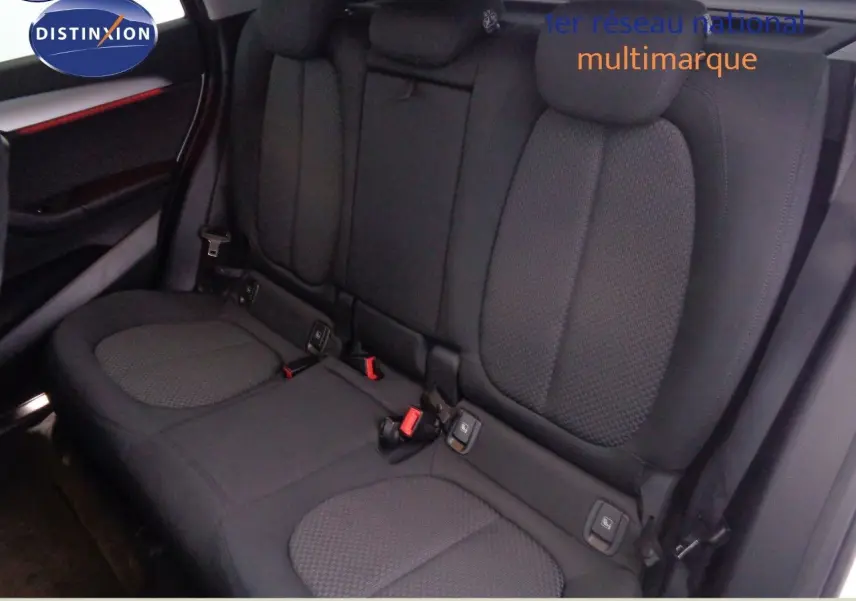 Vue intérieure arrière des sièges noirs en tissu du BMW X1 2022, mettant en valeur les appuie-têtes et ceintures de sécurité.