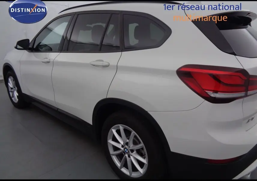 BMW X1 blanc Alpine métal vu de profil côté gauche, mettant en valeur les feux arrière et les jantes alliage.