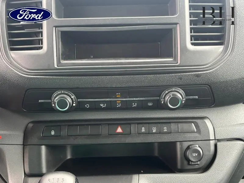 Tableau de bord du Peugeot Expert Fourgon blanc, montrant les commandes de climatisation et la prise 12V en gros plan.