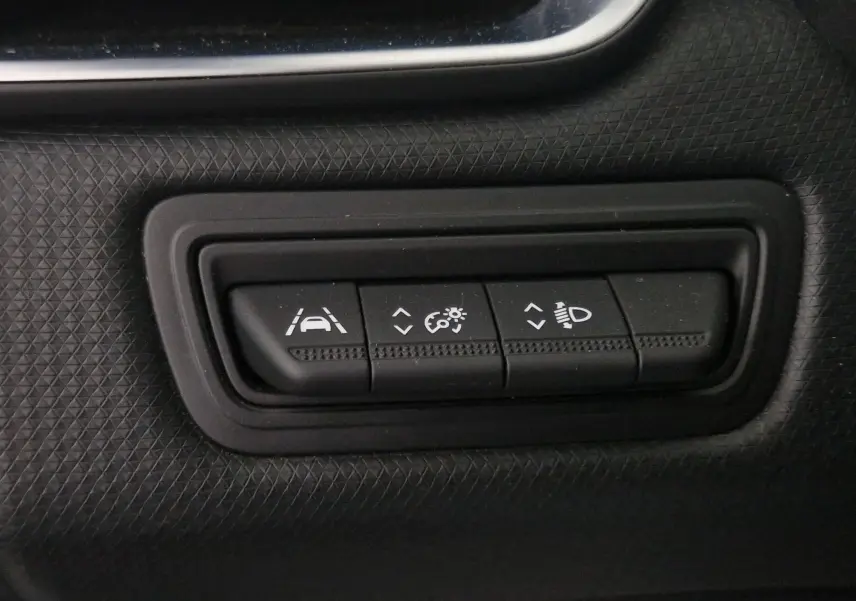 Gros plan sur les boutons de réglage d'assistance et d'éclairage dans une Renault Clio V gris platine de 2021.