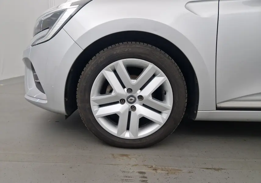 Gros plan sur la roue avant gauche d'une Renault Clio V gris platine, mettant en valeur la jante au design moderne.