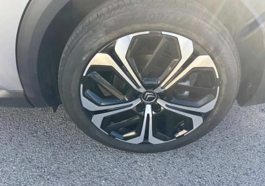 Gros plan sur la jante alliage 19 pouces noire et argentée d'une Citroën C5 X gris foncé, côté roue avant.