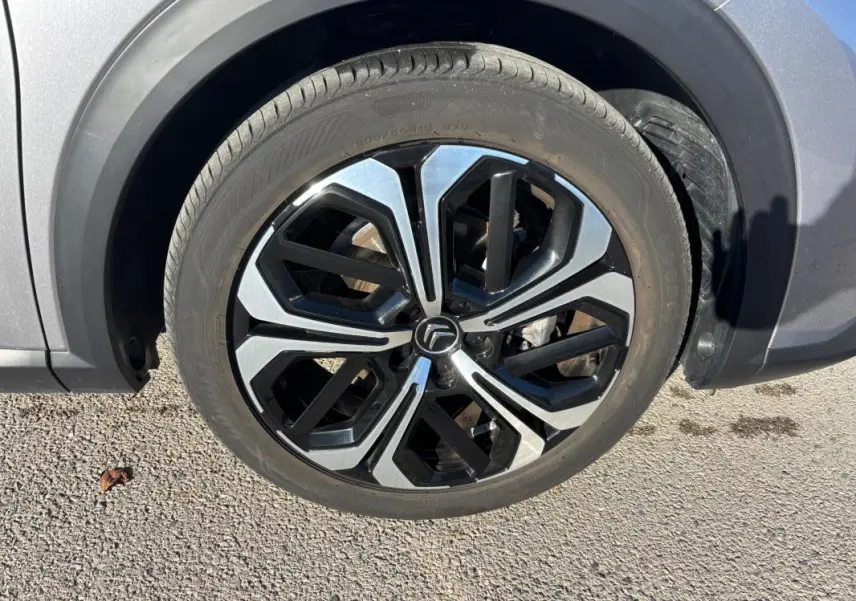 Gros plan sur la jante alliage 19 pouces noire et argentée du côté avant droit d'une Citroën C5 X gris foncé.