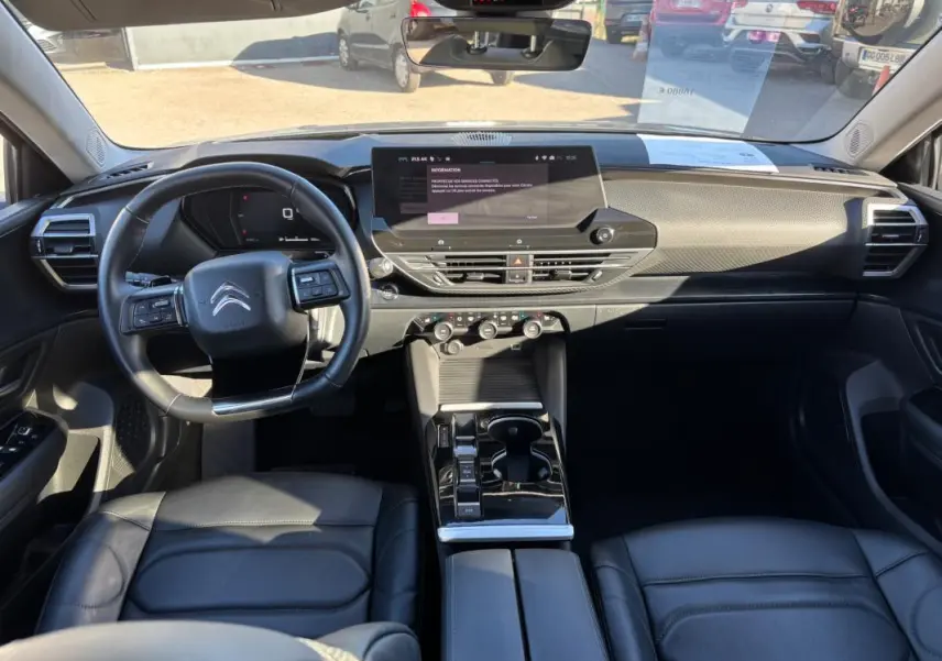 Vue intérieure avant de la Citroën C5 X 2024, tableau de bord moderne avec écran tactile et volant cuir noir.