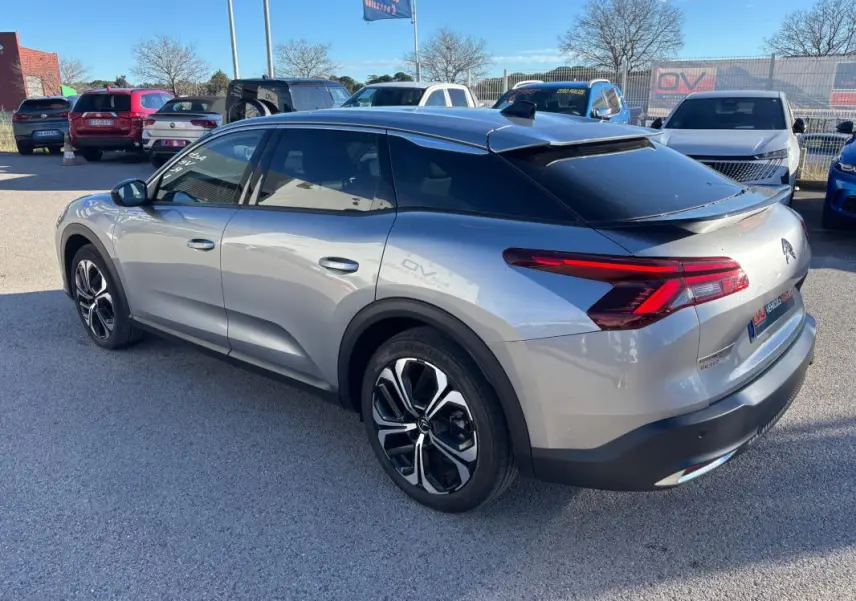 Vue 3/4 arrière droite d'une Citroën C5 X gris foncé avec jantes alliage 19 pouces et toit noir contrasté.